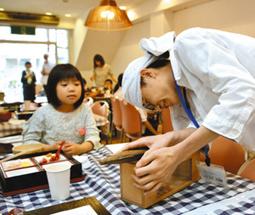 子どもたちの前でかつお節を削りだす学生（右）＝５月２６日、大垣市郭町で