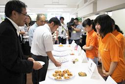 ニンジンを生かした料理やお菓子を薦める学生（右）ら＝各務原市の東海学院大で