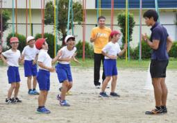 品田さん(右)から正しい腕の振り方を教わる児童ら=関市武儀西小で