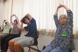 ストレッチをする学生と高齢者=6月25日、四日市市萱生町の四日市大で