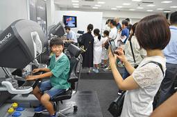 ダヴィンチ（左）の操縦席に座り、記念撮影する親子＝豊明市の藤田保健衛生大で