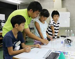 ペットボトルに入れた水の量などをグラフに書き込む児童ら=野々市市の金沢工業大で