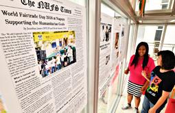 多くの人に読んでもらおうと、拡大して学内に張った英字新聞を眺めるエバンジェリスタさん（右）ら＝日進市の名古屋外国語大で