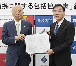 協定書を手にする尾西信金の木村理事長(左)と修文大の丹羽学長=一宮市日光町の同大で