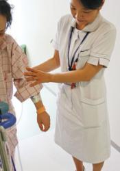 リストバンドを着けた術後の患者に付き添う看護師=愛知県豊明市の藤田医科大病院で