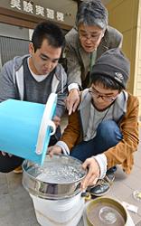 伊勢湾の海底の泥に含まれていた微細なものをふるいにかけ、マイクロプラスチックを探す千葉賢教授（奥）と学生たち＝三重県四日市市の四日市大で