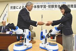 米田委員長（右端）に顕微鏡の目録を手渡す森居会長＝長浜市の長浜バイオ大で