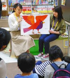 カラフルな動物が登場する英語の絵本で、読み聞かせをする学生たち=日進市赤池町で