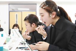 教わった手順通りに化粧を施す学生たち＝大垣市の大垣女子短大で