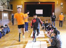 池田選手に教わりながらスポーツ義足を体験する児童＝豊橋市嵩山町宮下の嵩山小で