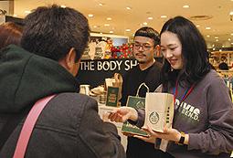 買い物客に手づくりのカードを手渡す学生（右）＝中区栄三で