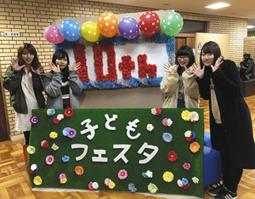 来場者を迎えるウエルカムボードと、角さん（左から２人目）ら実行委員のメンバー＝稲沢市稲葉の愛知文教女子短大で