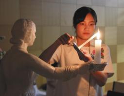 ナイチンゲール像から火をろうそくにともす学生＝一宮市常願通５の一宮研伸大で