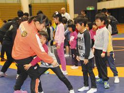至学館大の選手からタックルを教わる子どもたち＝大府市のメディアス体育館おおぶで