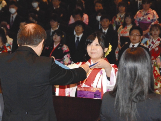 卒業生を代表して学位記を受け取る木下さん（中）＝鈴鹿市南玉垣町の鈴鹿医療科学大で