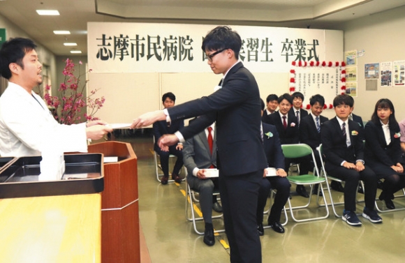 病院で研修した学生に卒業証書を手渡す江角院長（左）＝志摩市大王町の志摩市民病院で