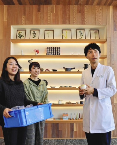 自作の湯飲みを運び込む江草さん（左）と尾関さん。右は上西さん＝小牧市常普請２の上西内科で