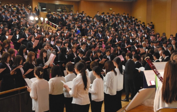 谷川賢作さんの指揮で学歌を歌う新入生ら＝いずれも大垣市の岐阜協立大で