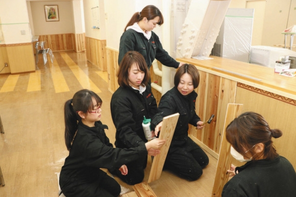 根羽杉の板材に木工用接着剤を塗り、一枚一枚丁寧にはめ込む学生たち=岐阜市太郎丸で