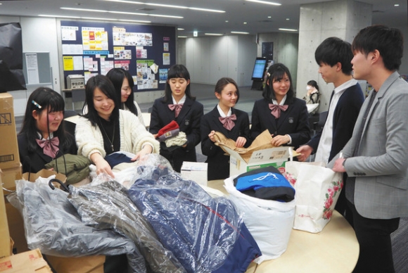 寄付された古着やタオルなどを仕分ける同朋高生と愛知大生たち＝中村区の同大で