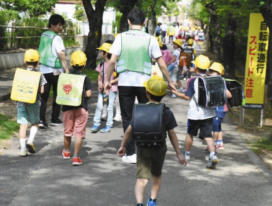 大学生ボランティアらに付き添われて下校する児童たち＝みよし市三好丘小で