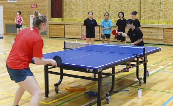スロバキア代表選手(手前)とラリーする中学生=岐阜市柳津町下佐波西の市もえぎの里多目的体育館で