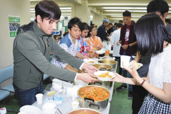料理でもてなすネパール出身の学生ら（左側）＝犬山市の名古屋経済大で