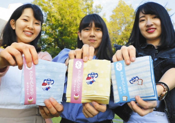 完成した「ドアラハンカチ」を手にする広告研究会の学生たち＝名古屋市守山区の金城学院大で