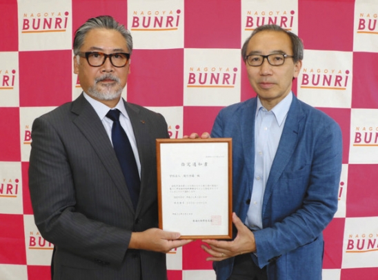 堀江局長（右）から通知書を受け取る滝川理事長＝名古屋市西区の名古屋文理大短大で